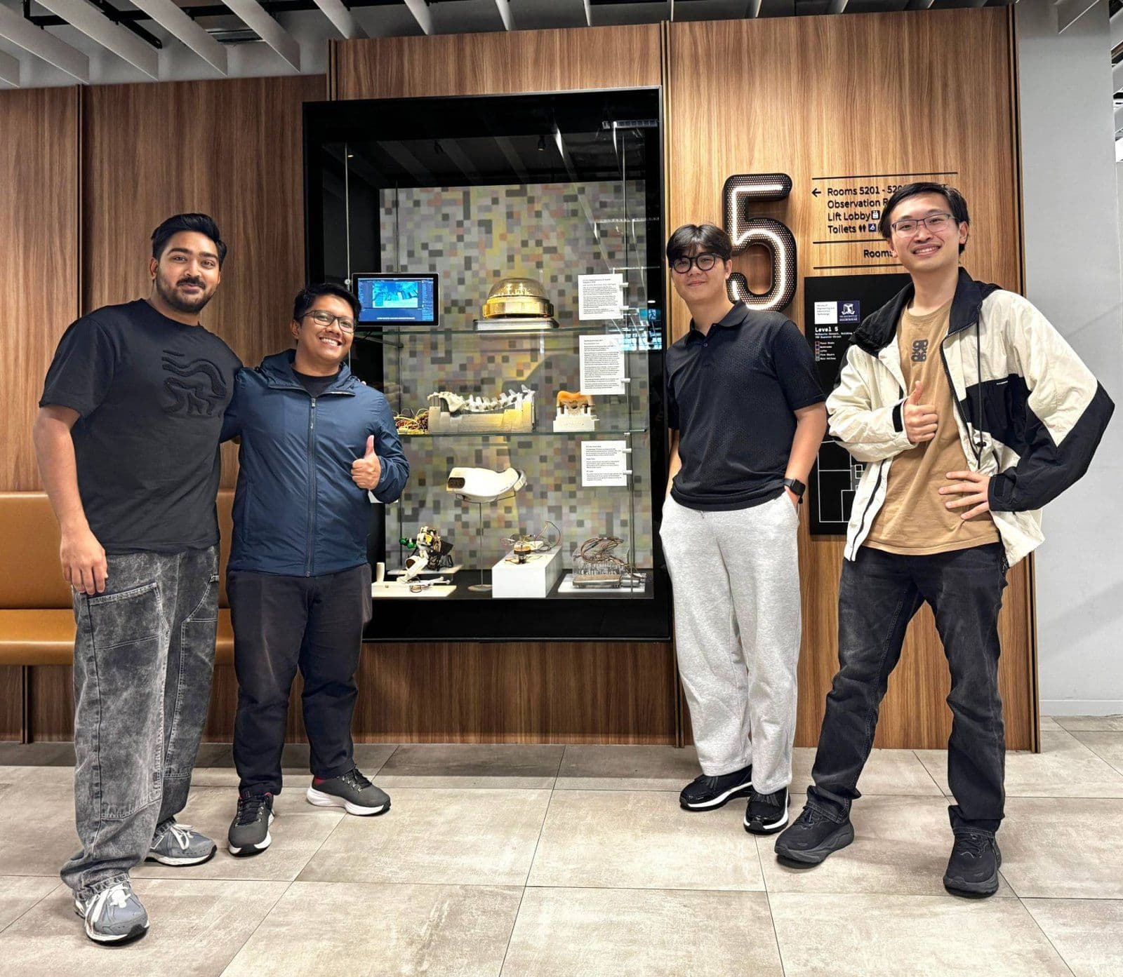 Kevin Bryan and three teammates beside a project display case at Melbourne Connect