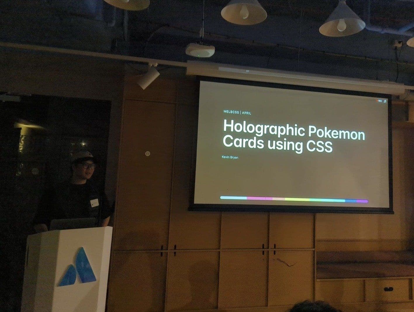 Kevin Bryan at a lectern beside a projected slide titled Holographic Pokemon Cards using CSS
